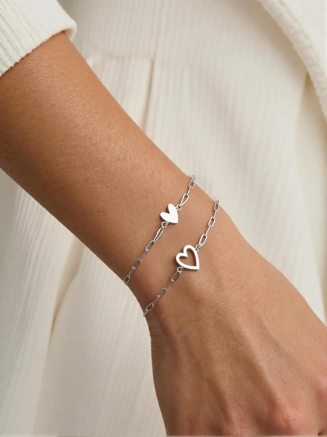 Gold heart bracelet worn on woman's wrist with elegant styling