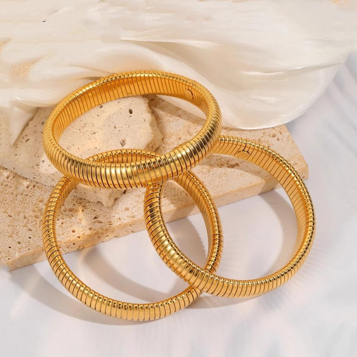 Close-up of flexible 24K gold plated chunky bangles on wrist