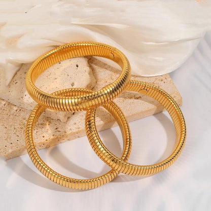 Close-up of flexible 24K gold plated chunky bangles on wrist