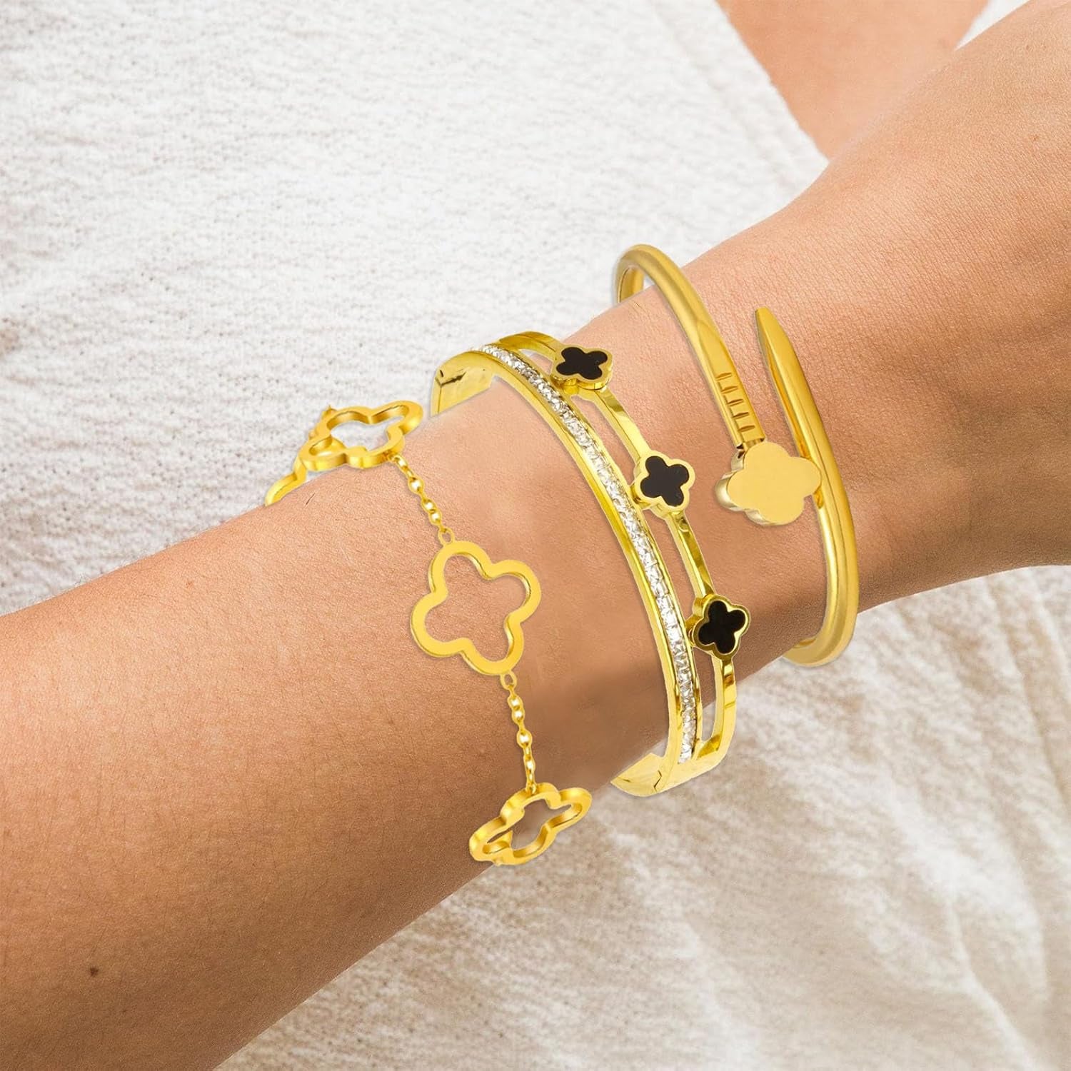 Multiple gold clover bracelets stacked together on wrist
