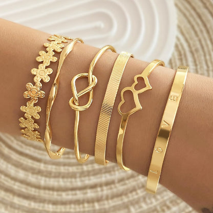Close-up of smooth polished gold bangles stacked together on wrist