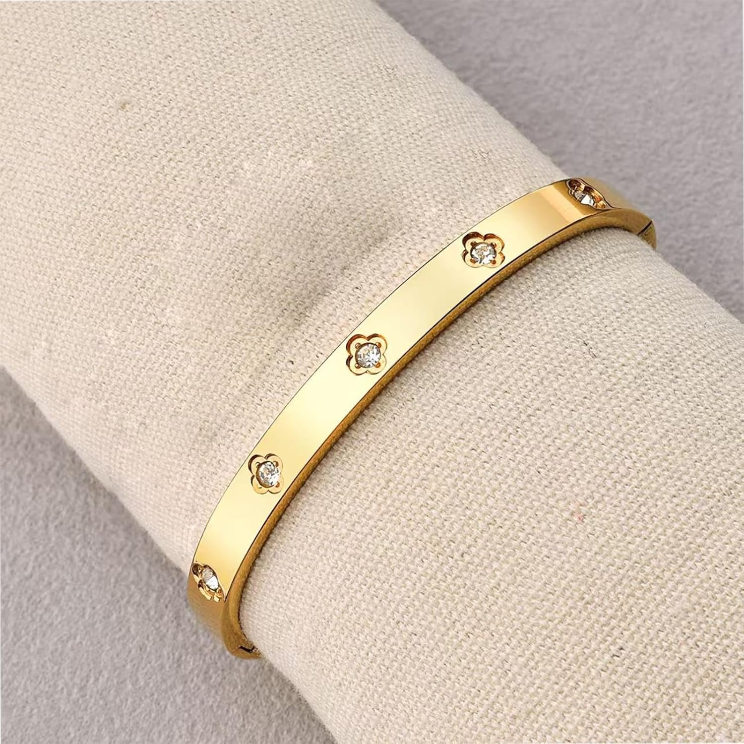 Woman's wrist wearing gold plated clover love bangles