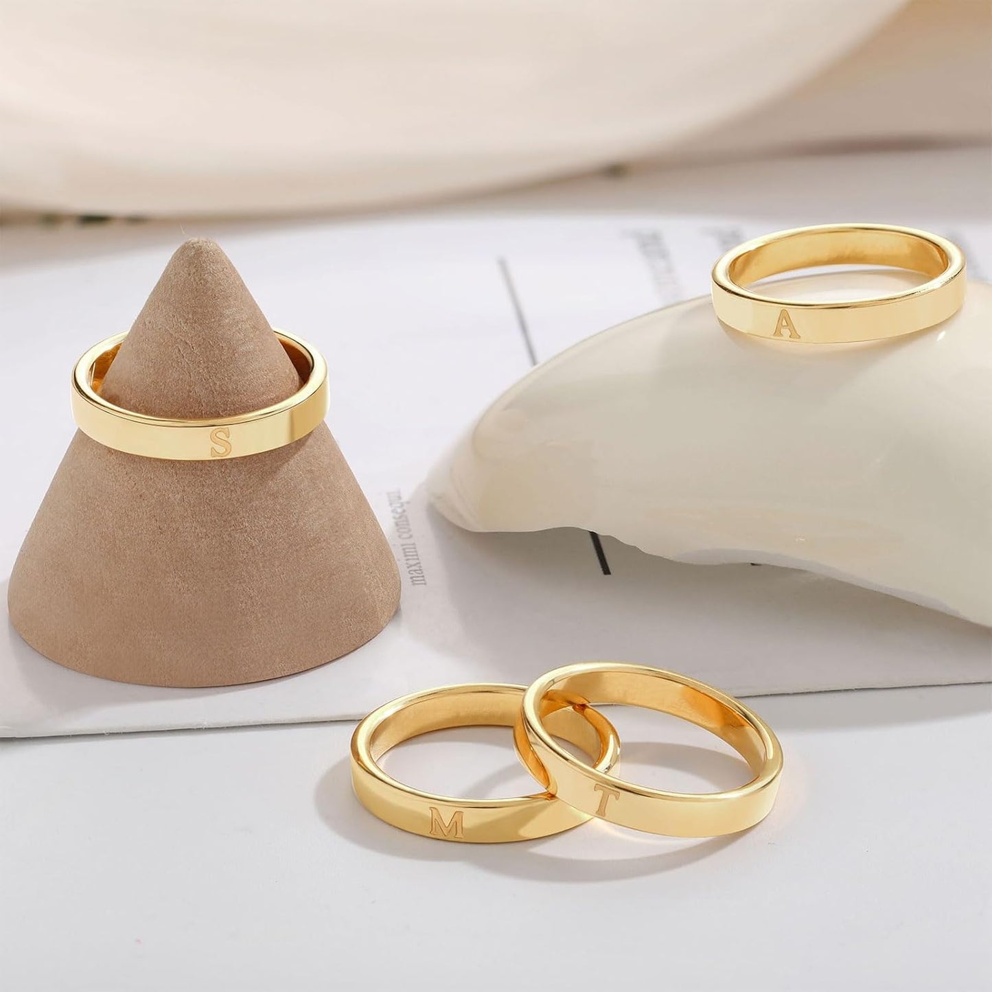Woman modeling stacked gold initial rings on thumb and pinky