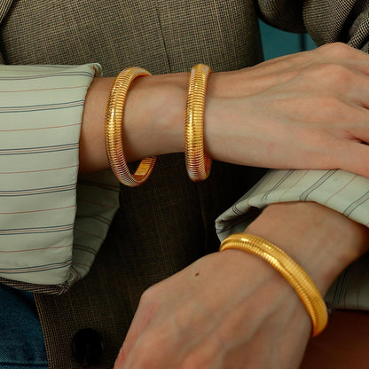 Gold chunky bangles worn as stacked bracelet set
