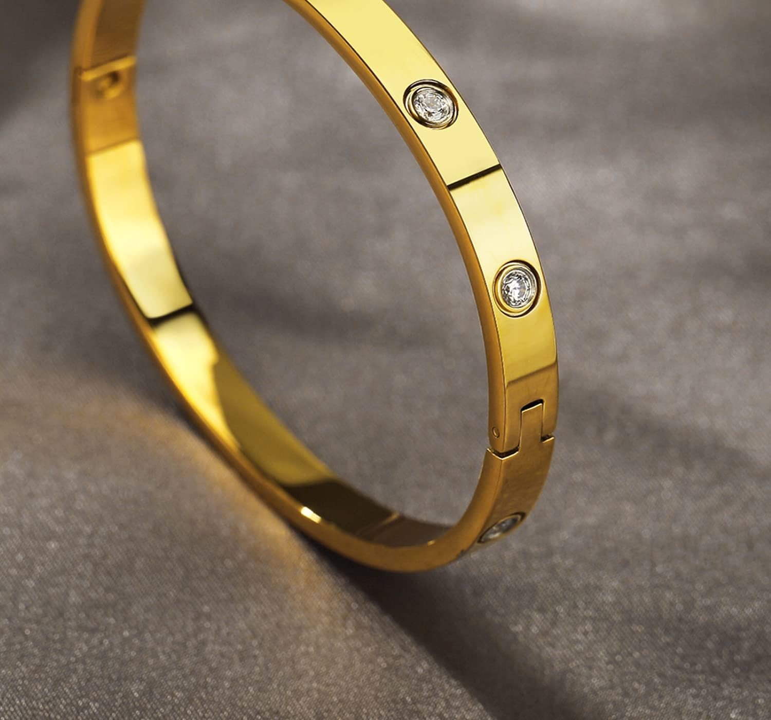 Women wearing gold love bangle bracelet as part of jewelry stack