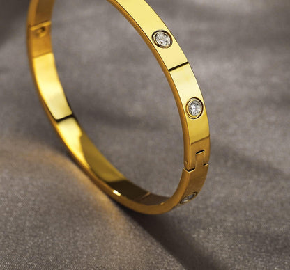 Women wearing gold love bangle bracelet as part of jewelry stack