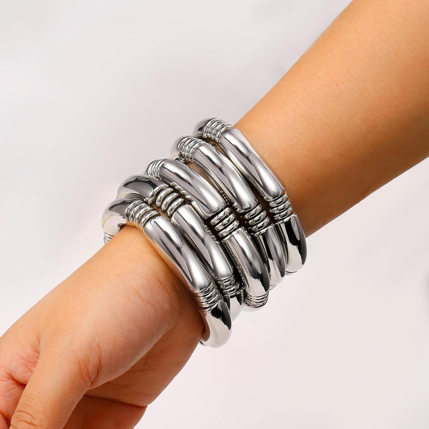 Multiple gold chunky bangles worn together as layered jewelry