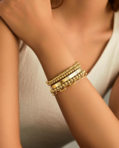 Gold plated beaded bracelets worn together demonstrating layered styling