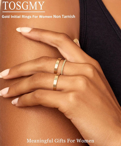 Woman wearing stacked gold initial rings on multiple fingers