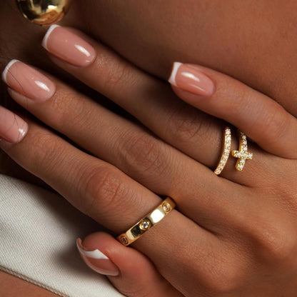 Dainty gold cross rings stacked together showing love cubic zirconia details