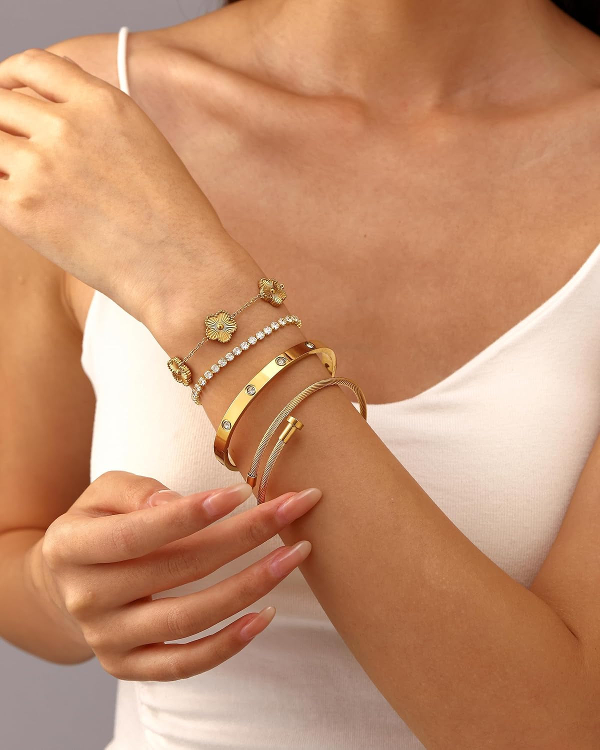 Close-up of 18K gold plated non-tarnish bangle bracelets stacked on woman's wrist